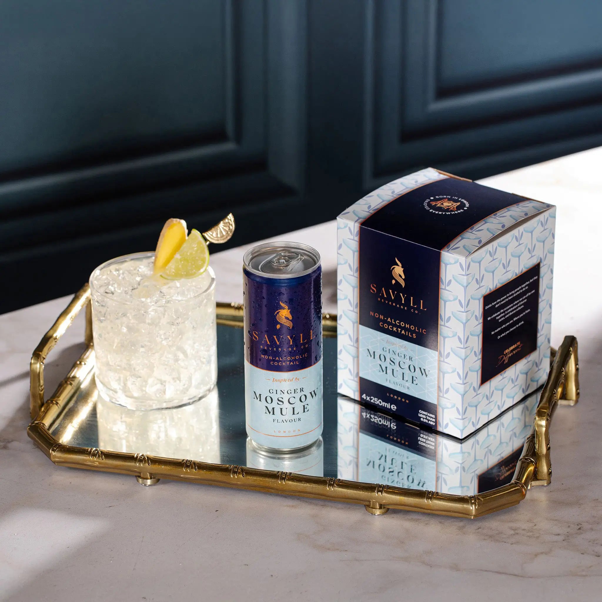 Savyll alcohol-free Ginger Moscow Mule 4-pack with a can and a glass of iced cocktail garnished with lemon and lime on a gold tray.