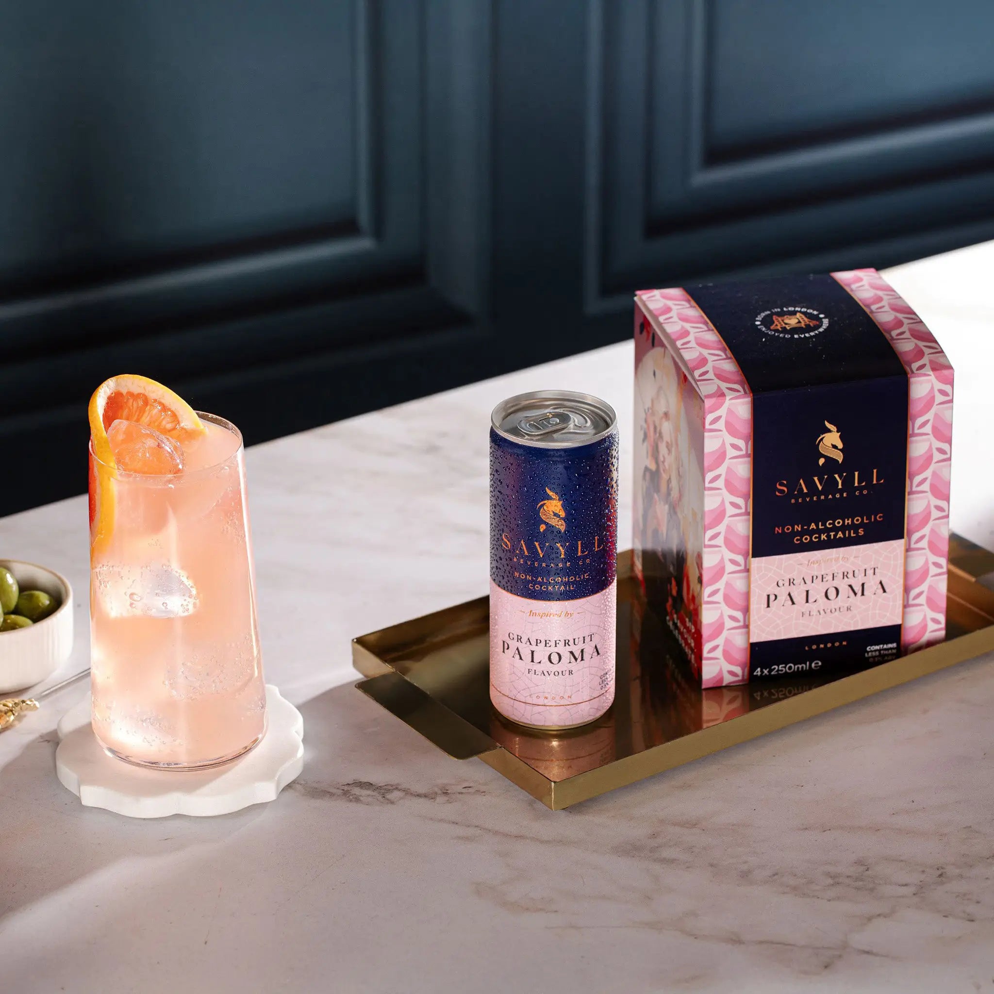 Four-pack of Savyll non-alcoholic grapefruit Paloma cocktails with one can and a glass garnished with grapefruit slices.