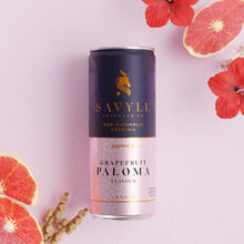 Can of Savyll non-alcoholic grapefruit Paloma cocktail with grapefruit slices and red flowers on a pink background.